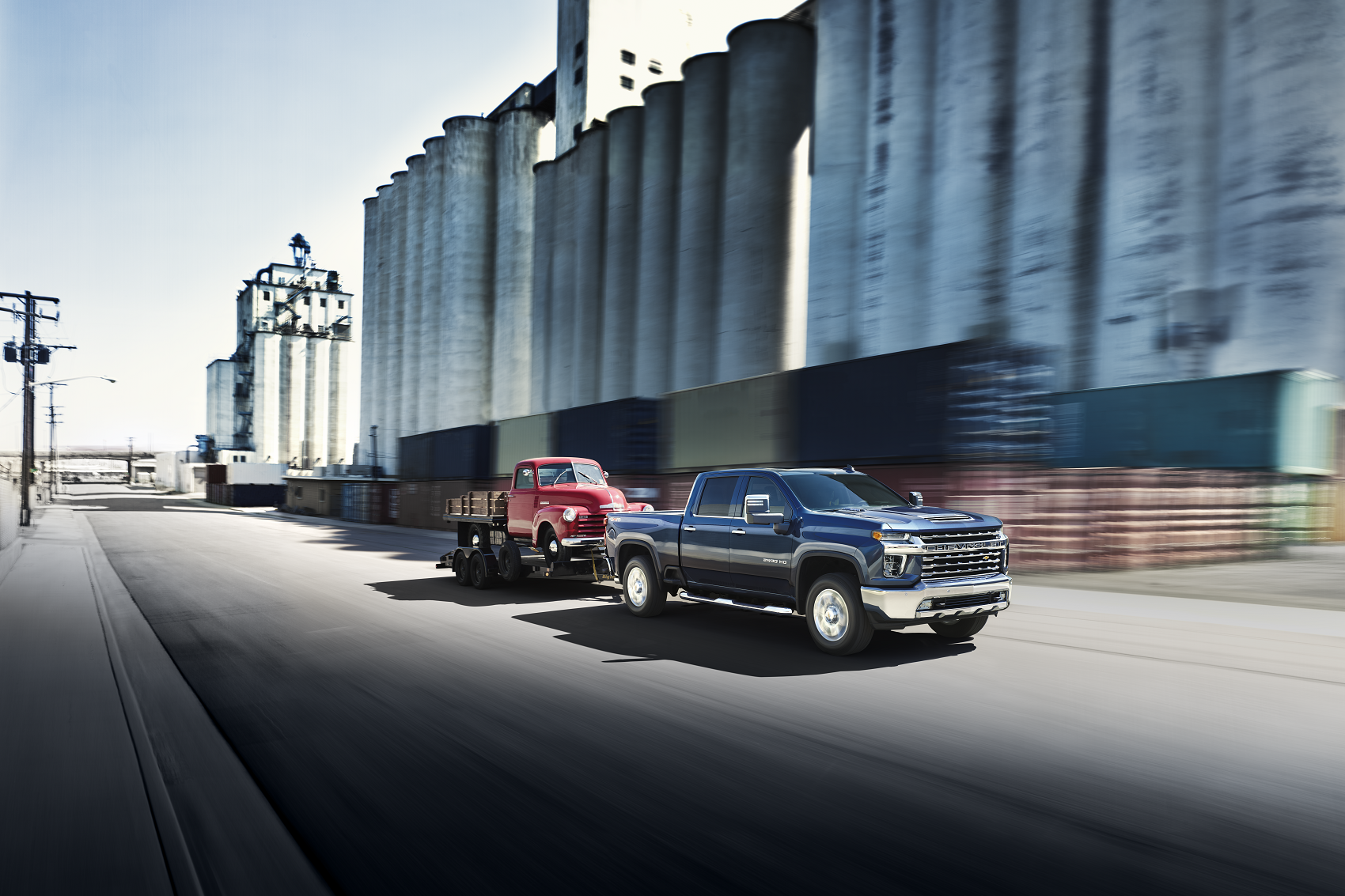 With a maximum towing capacity of 18,500 pounds, a black Chevy Silverado 2500 easily tows a trailer with a vintage red truck